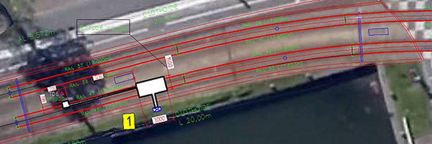 Vue aérienne d'un site traversé par des voies, avec un plan technique annoté de lignes rouges, de repères et de cotes en vert.